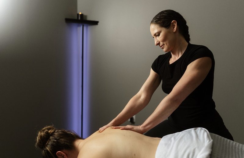 Vivian working across a client's back in the dimly lit treatment room